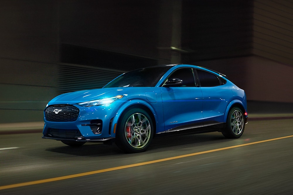 Un'auto sportiva elettrica Ford Mustang Mach-E-GT blu percorre una strada aperta.