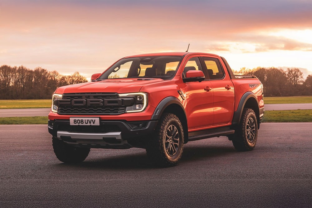 Un pick-up Ford Ranger Raptor arancione parcheggiato in un paesaggio panoramico.