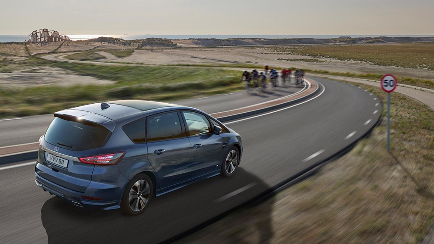 Ford S-MAX in movimento su una strada che costeggia una spiaggia