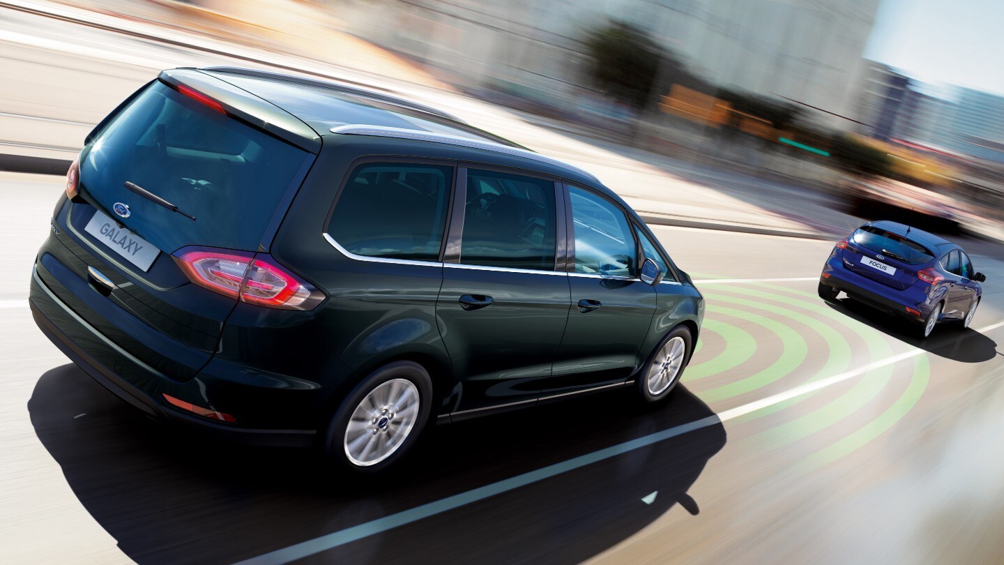Ford S-MAX nera che guida in città con assistenza pre-collisione mostrata