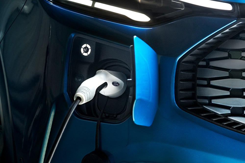 Primo piano della porta di ricarica di un Ford Tourneo Cutstom blu con il cavo di ricarica collegato.