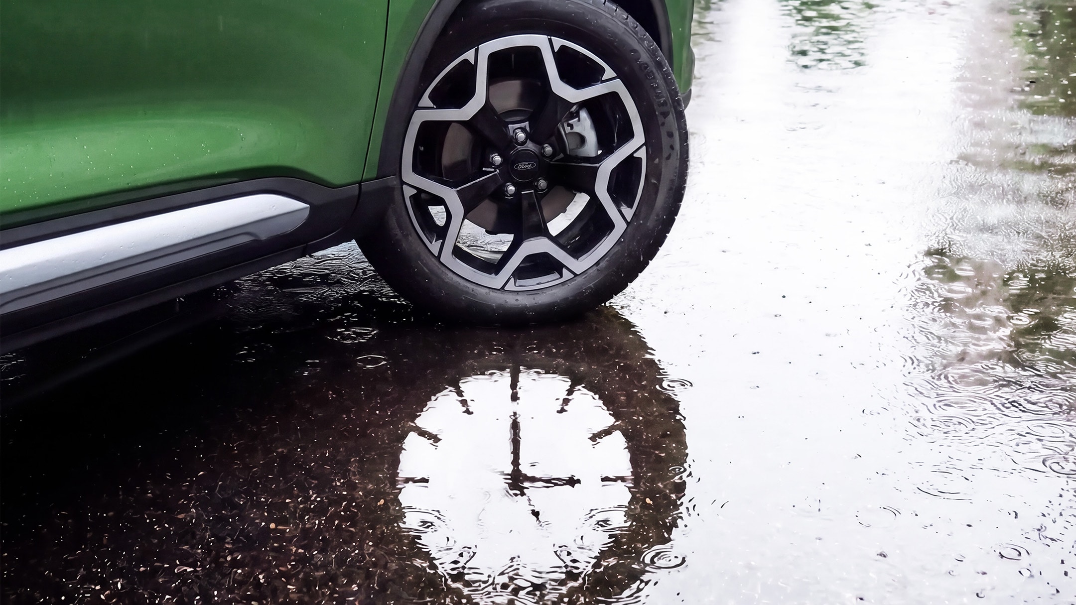 La roue avant d’un véhicule Ford Kuga vert se trouve à côté d’une flaque d’eau.
