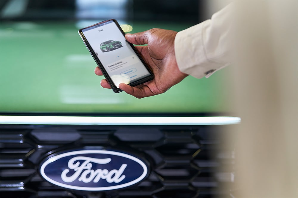 Uomo che guarda lo smartphone con l'app Ford visualizzata