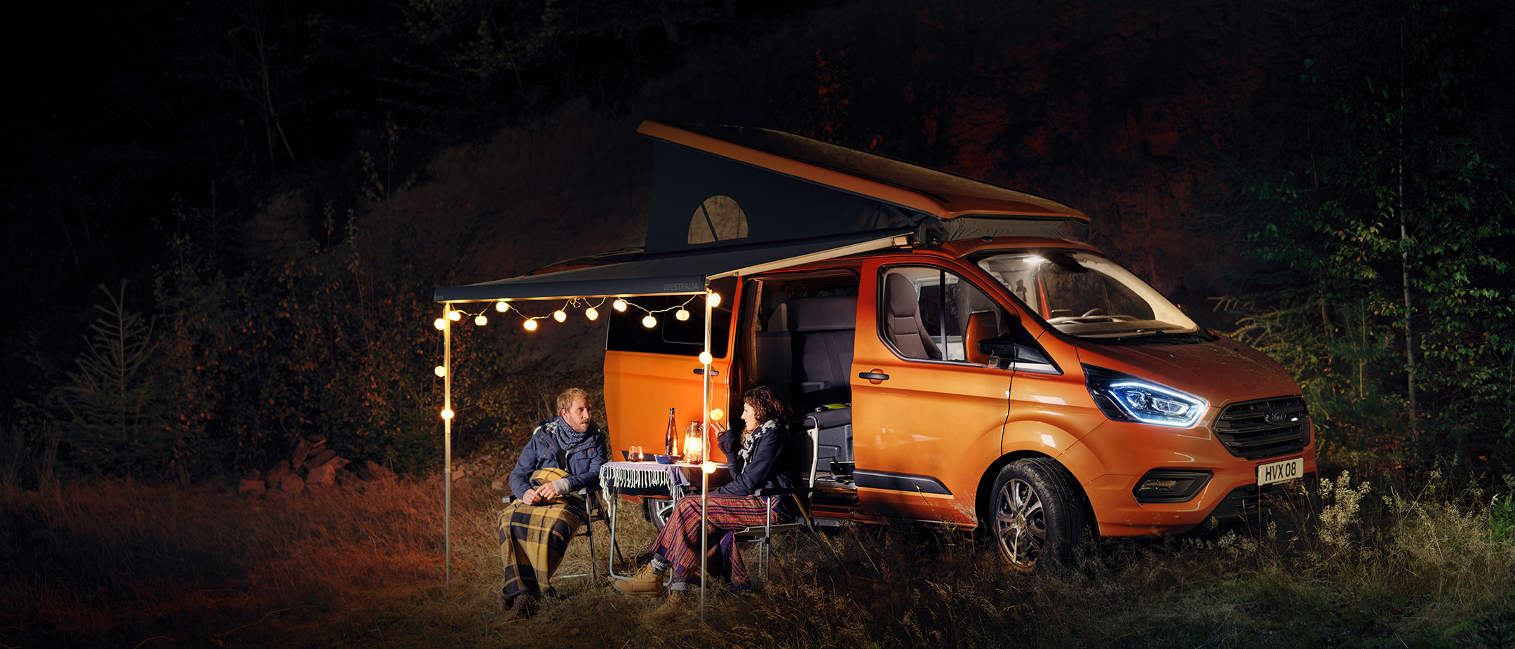 Ford Transit Custom Nugget arancione con coppia in campeggio