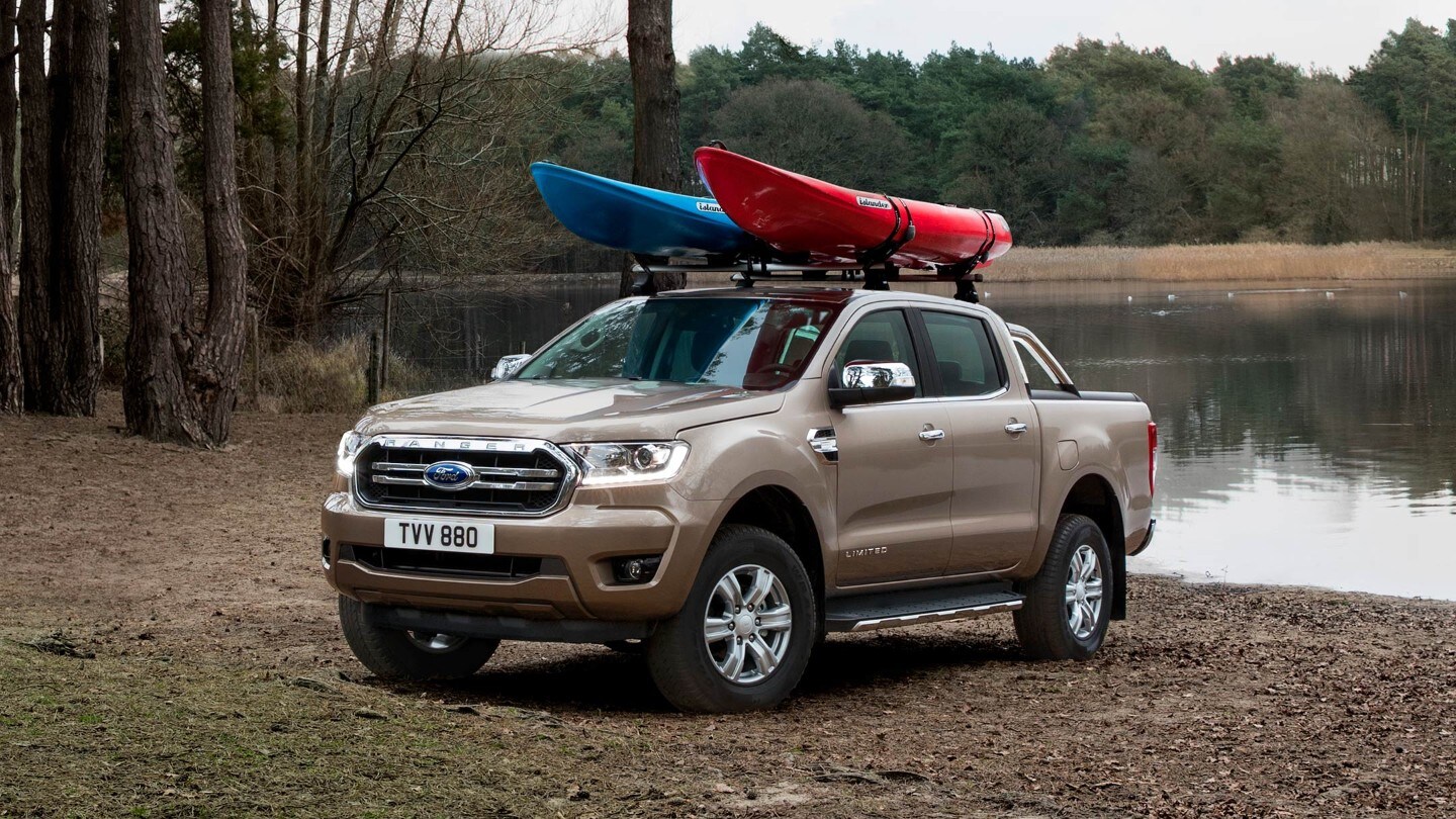 Silver Ford Ranger Wildtrak loaded with canoes parked near lake