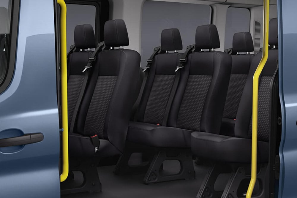 Interior of a Ford Transit Minibus showing black passenger seats and a yellow grab handle near the open door.