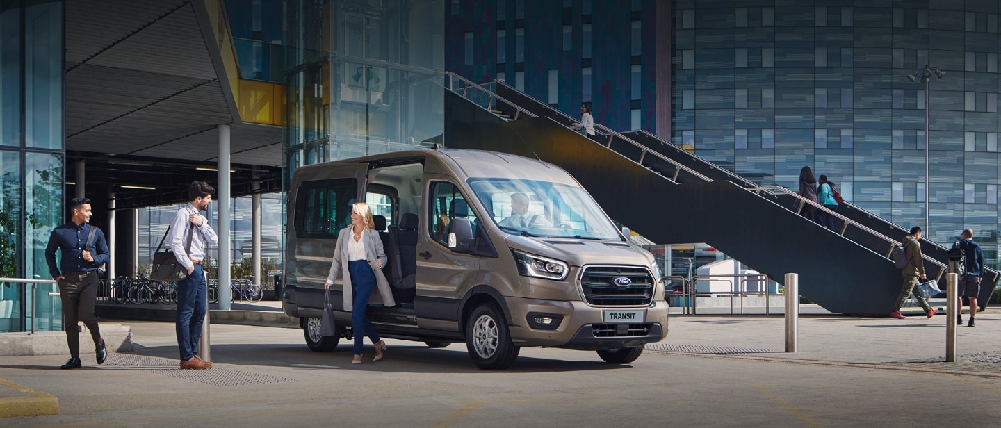 Ford Transit Minibus parcheggiato all'esterno di un edificio in vetro Ford Transit Minibus parcheggiato all'esterno di un edificio in vetro