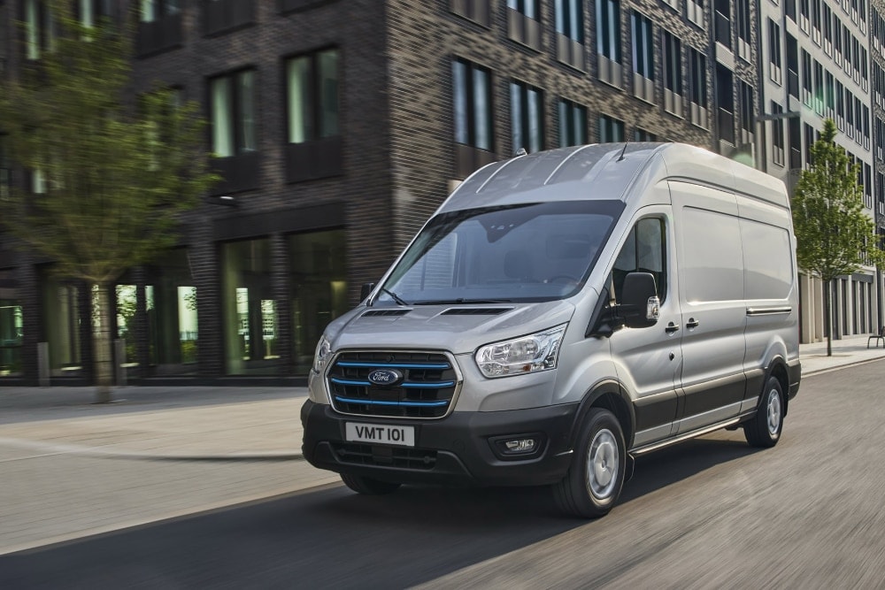 Furgone Ford E-Transit argento in movimento su strada urbana.