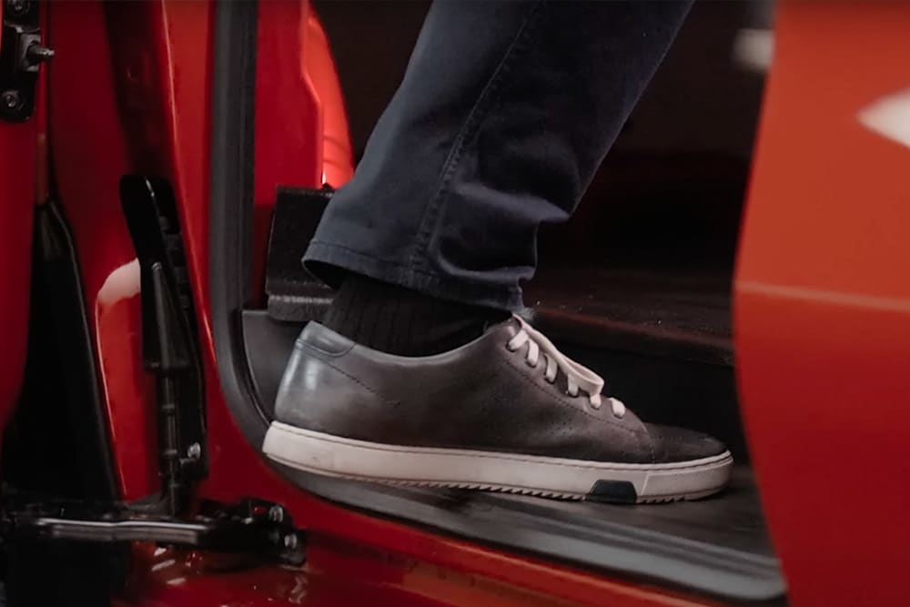 Immagine di un piede mentre sale su un Ford Transit Custom rosso.