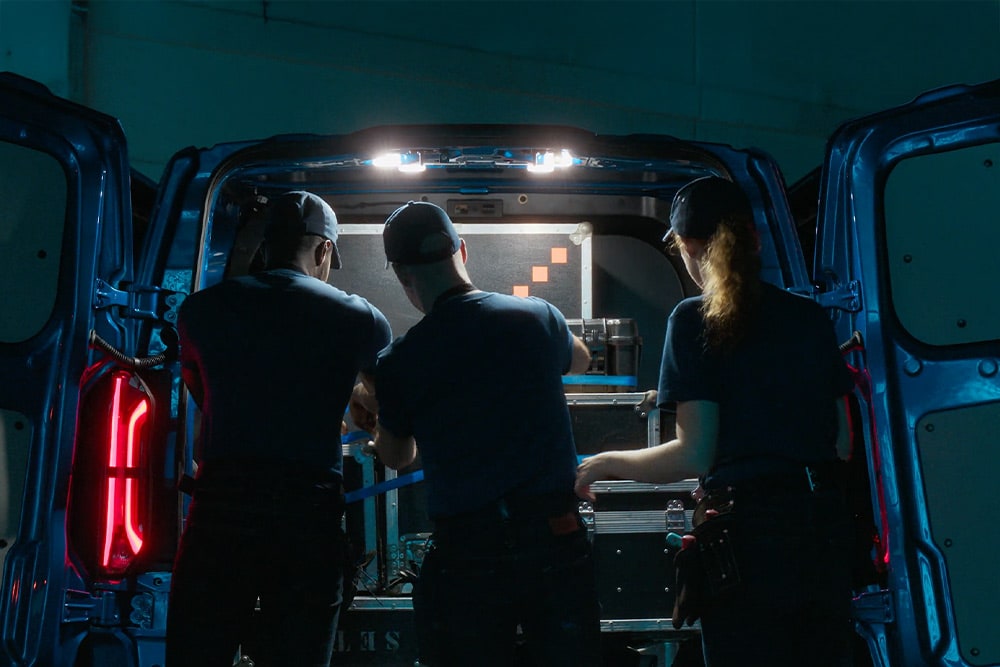 Tre persone lavorano nel retro di un furgone Ford Transit Custom.