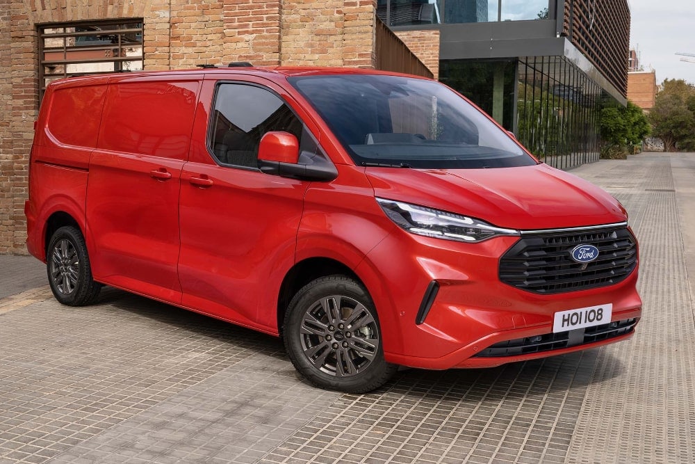 Furgone Ford Transit Custom rosso parcheggiato in un vicolo cittadino.