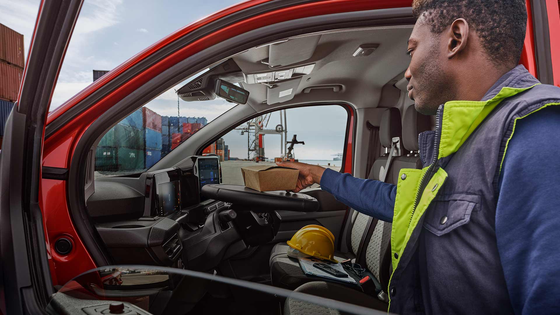 Una persona colloca un pacco all'interno di un Ford Transit Custom rosso.