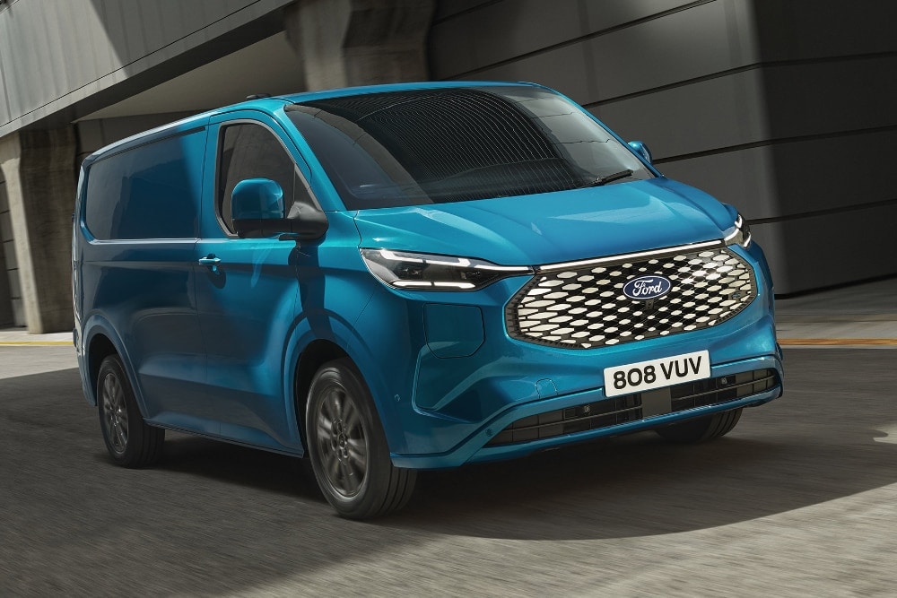 Furgone Ford E-Transit Custom blu in movimento su strada urbana.