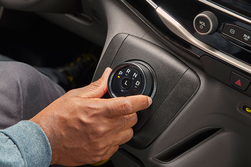 Primo piano di una mano che ruota il selettore delle marce in un furgone elettrico Ford E-Transit.