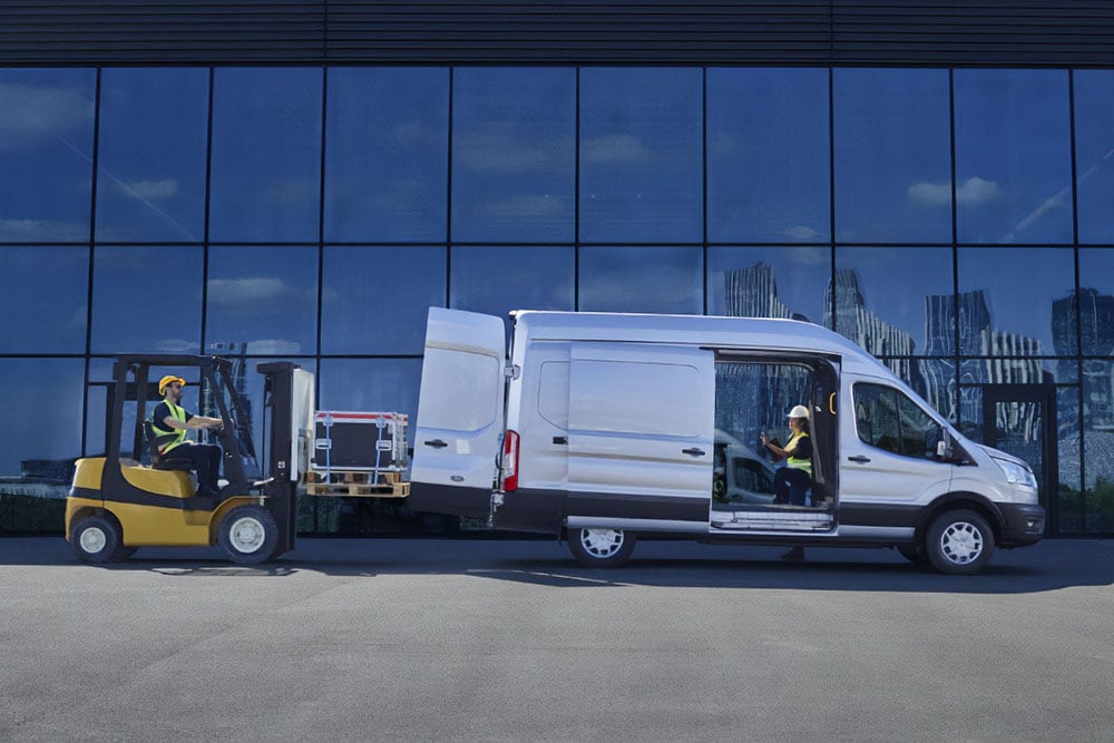 Due persone che utilizzano un muletto per caricare un furgone Ford Transit versione argento.