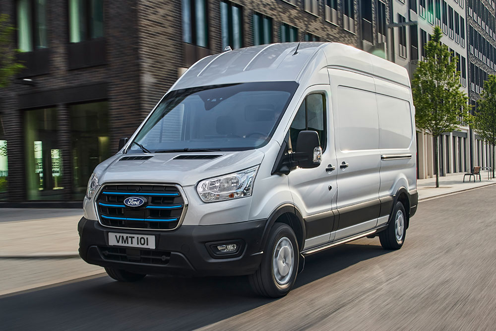Un Ford Transit color argento che attraversa un paesaggio urbano.
