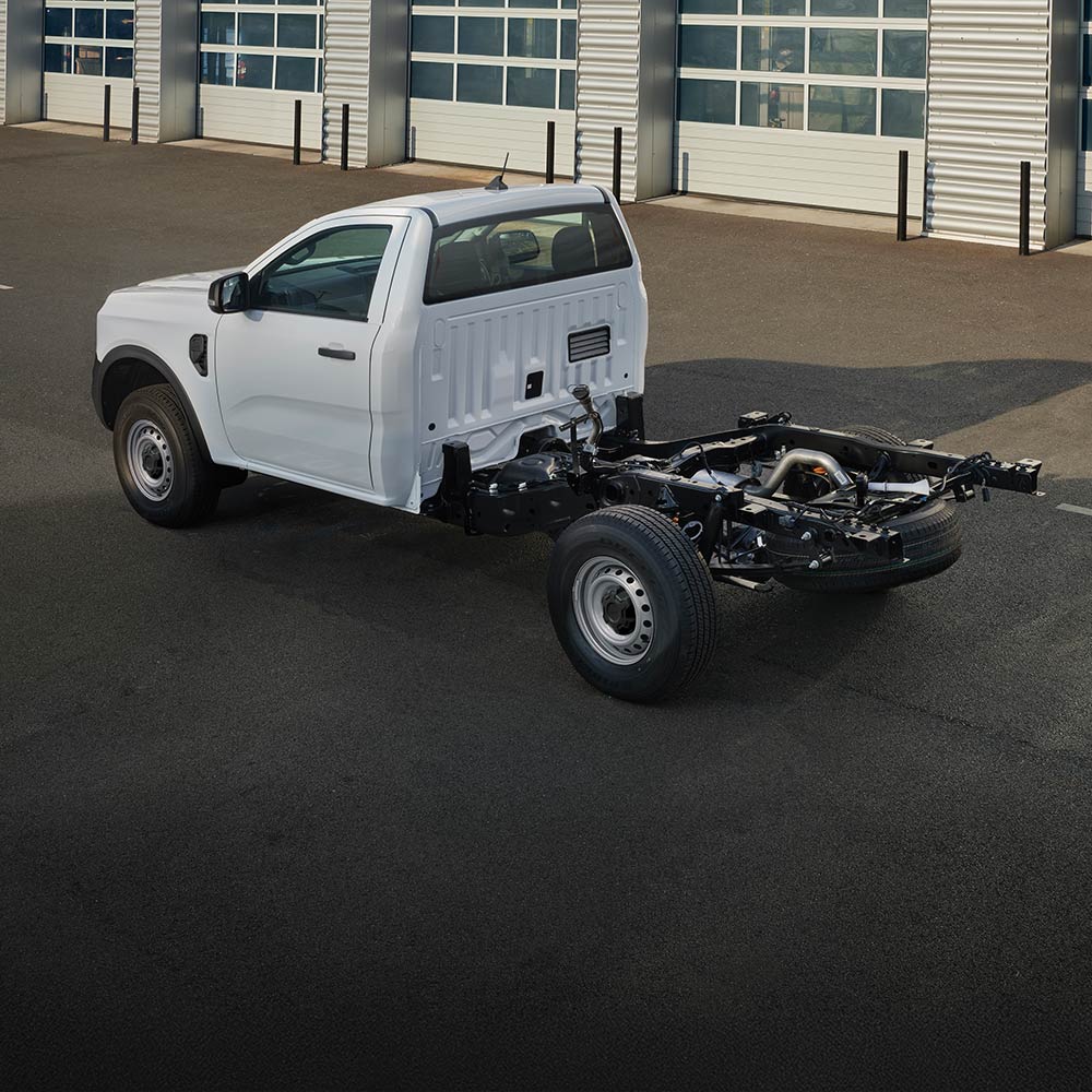 Un Ford Ranger Chassis Cab bianco parcheggiato davanti a una fila di porte del garage.