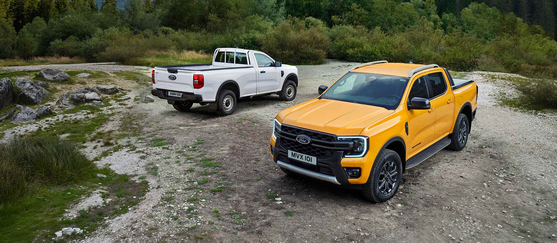 Un Ford Ranger bianco e un Ford Ranger giallo parcheggiati su un lato roccioso della strada. 