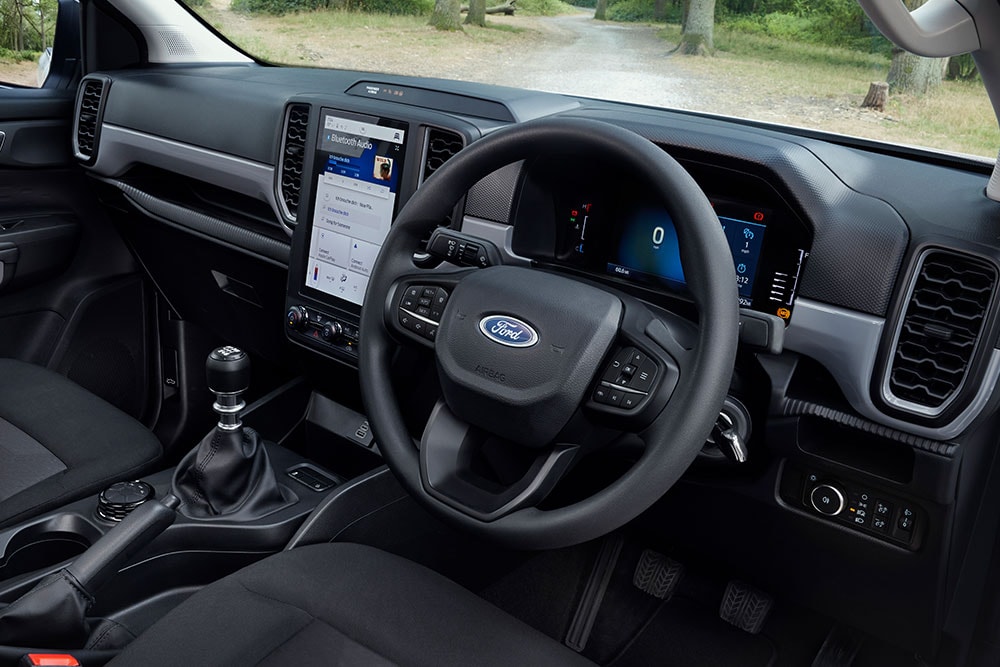 Vista sugli interni del Ford Ranger, che mostra il volante, la dashboard e la leva del cambio.