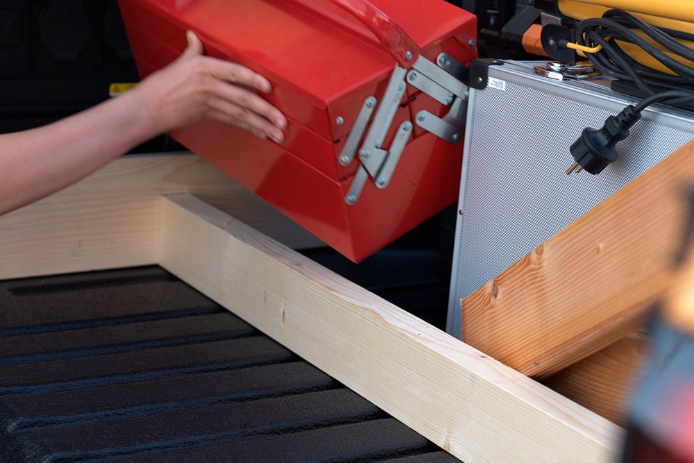 Close-up of a hand placing a red toolbox into the bed of a Ford Ranger.