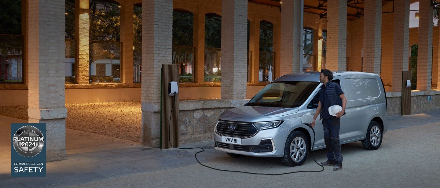 Uomo con un cappello rigido collega il cavo di ricarica di una wall box al nuovo Ford Transit Connect in Stardust Silver.