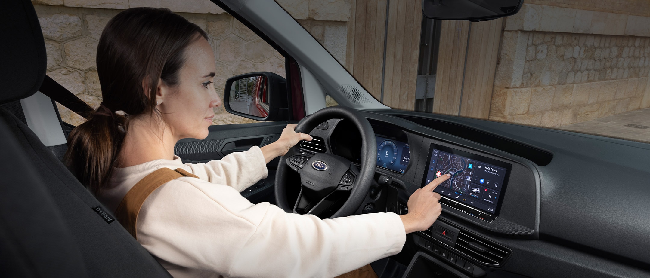 Una donna tocca il touchscreen da 10" mentre è seduta al posto di guida del nuovo Ford Transit Connect.