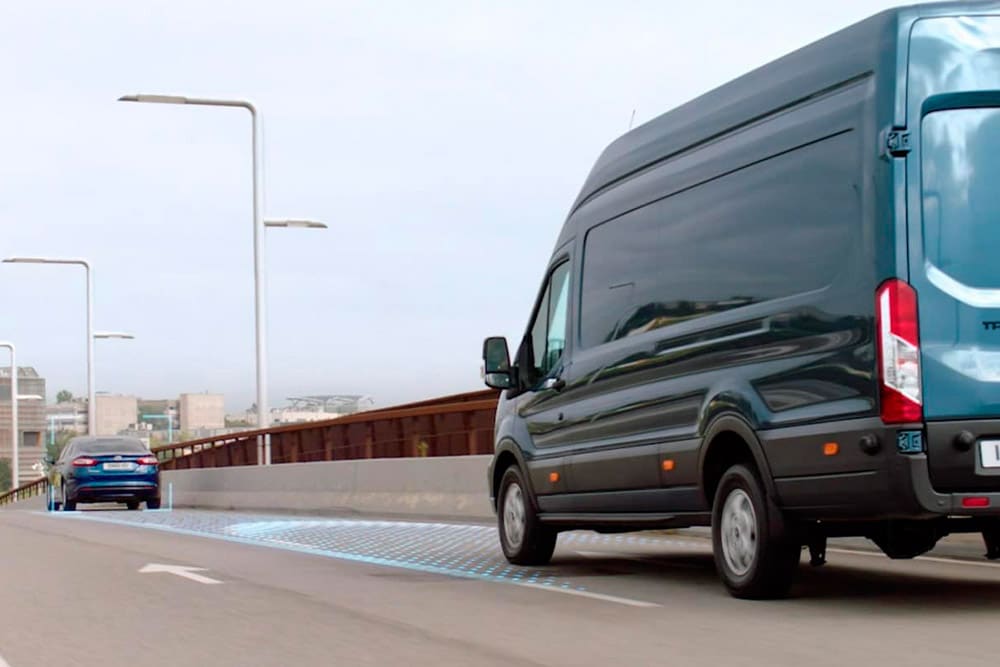 Furgone Ford Transit versione blu con le strisce blu sulla strada che segnalano l'utilizzo di Sistemi di assistenza alla guida.