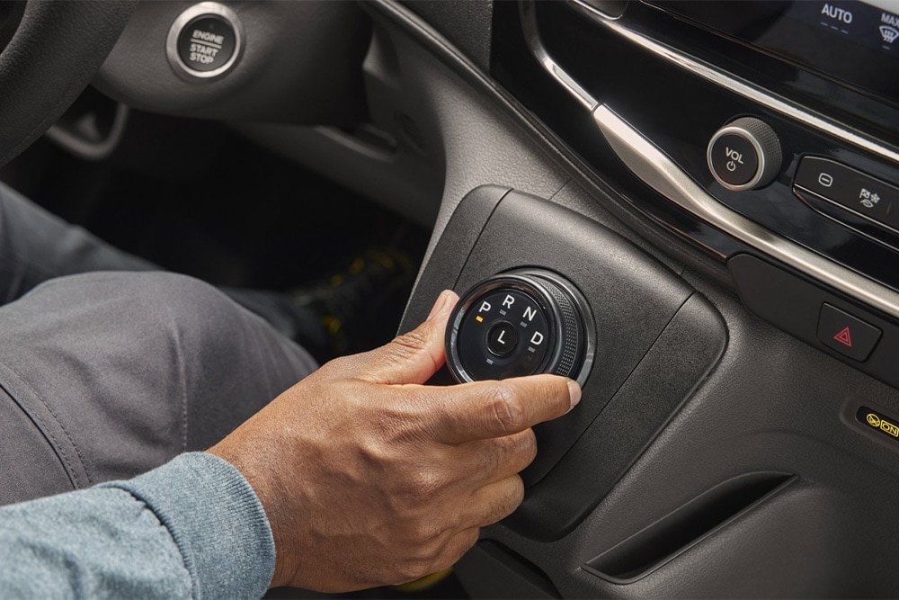 Mano che aziona il cambio rotativo nella console centrale di un furgone Ford Transit.