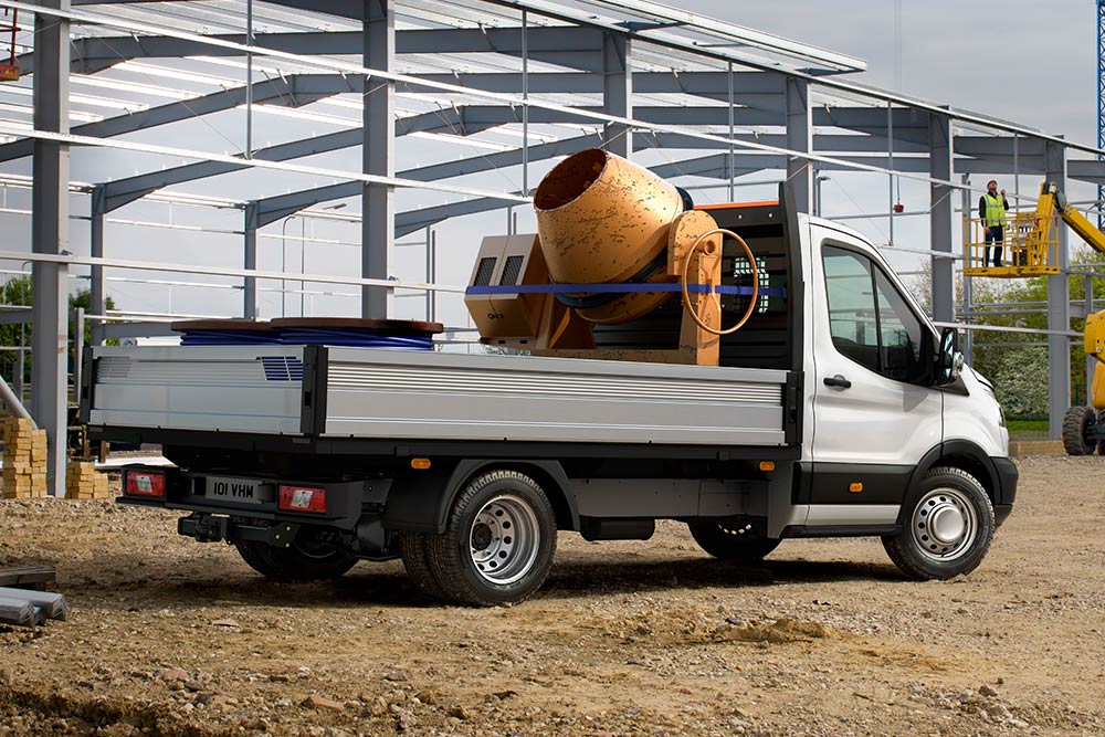 Ford Transit Chassis che trasporta una betoniera nel pianale di carico parcheggiato in un cantiere. 