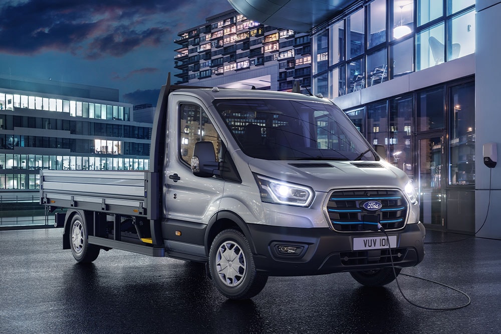 Ford E-Transit Chassis versione argento parcheggiato di fronte a un edificio moderno di notte.