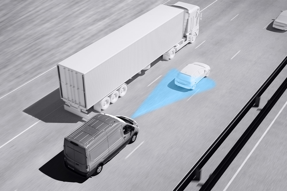 Scala di grigi raffigurante un furgone Ford Transit Chassis con le strisce blu sulla strada che mostrano l'utilizzo di Sistemi avanzati di assistenza alla guida.