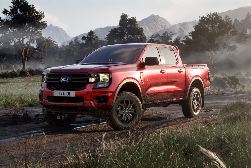 Un Ford Ranger Raptor rosso percorre una strada sterrata in un paesaggio panoramico.