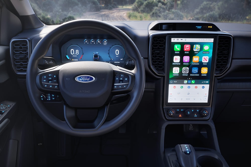 Vista sugli interni di un Ford Ranger Super Cab con volante, dashboard e schermo infotainment.