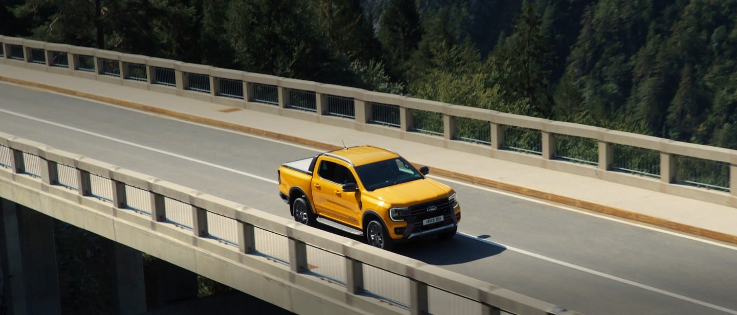 All-New Ford Ranger Wildtrak driving on bridge near mountains 3/4 front view