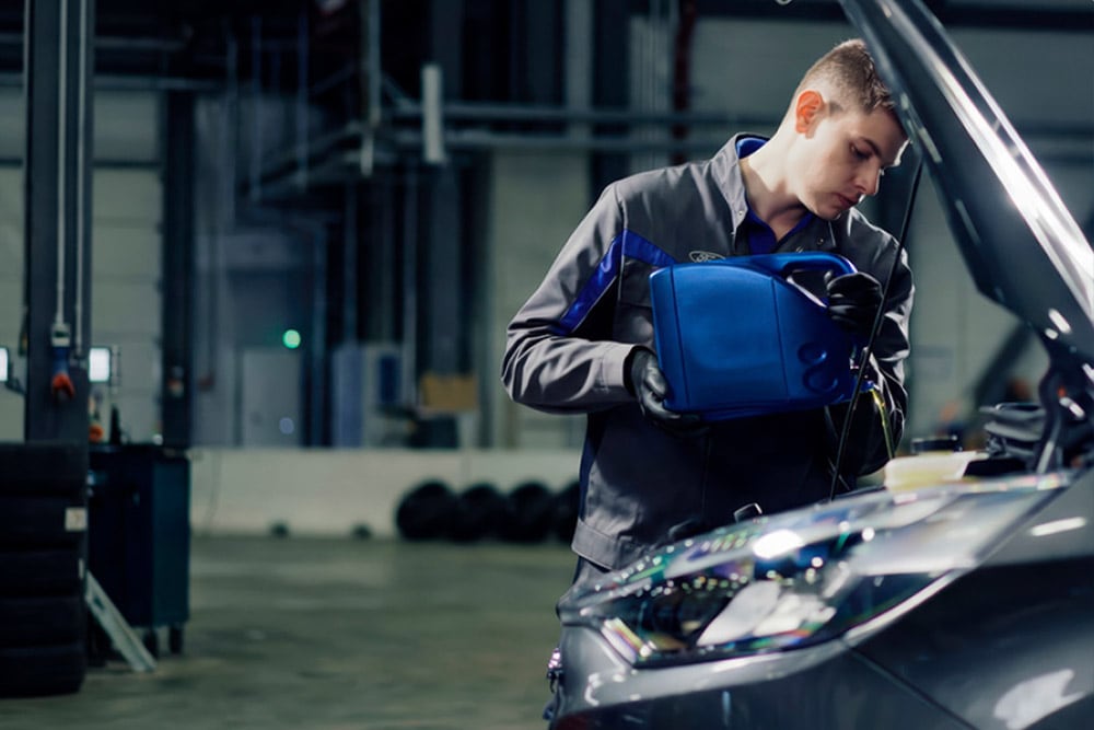 Vista laterale di un tecnico autorizzato Ford che effettua riparazioni su un veicolo in un'officina.