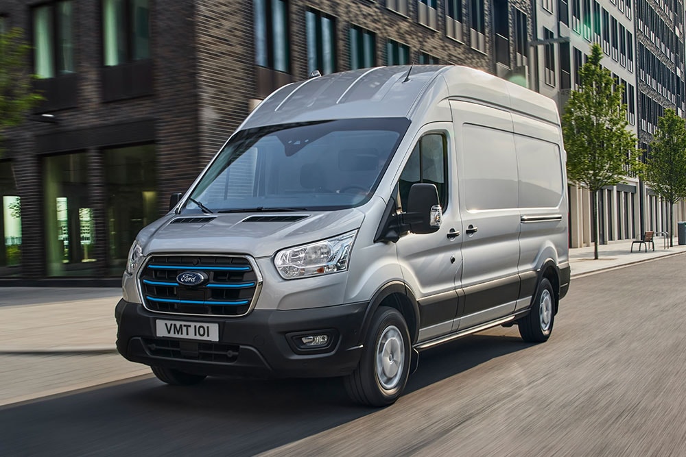 Un Ford Transit color argento che attraversa un paesaggio urbano.