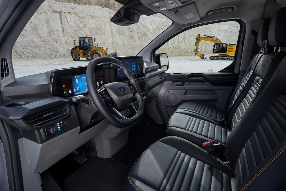 Vista sugli interni di un furgone Ford Transit Custom, che mostra il cruscotto, il volante e i sedili.