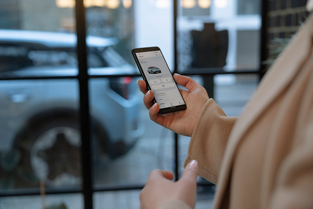 Una persona con in mano uno smartphone sul quale è visibile l'app FordPass con informazioni sulla gestione della flotta aziendale.