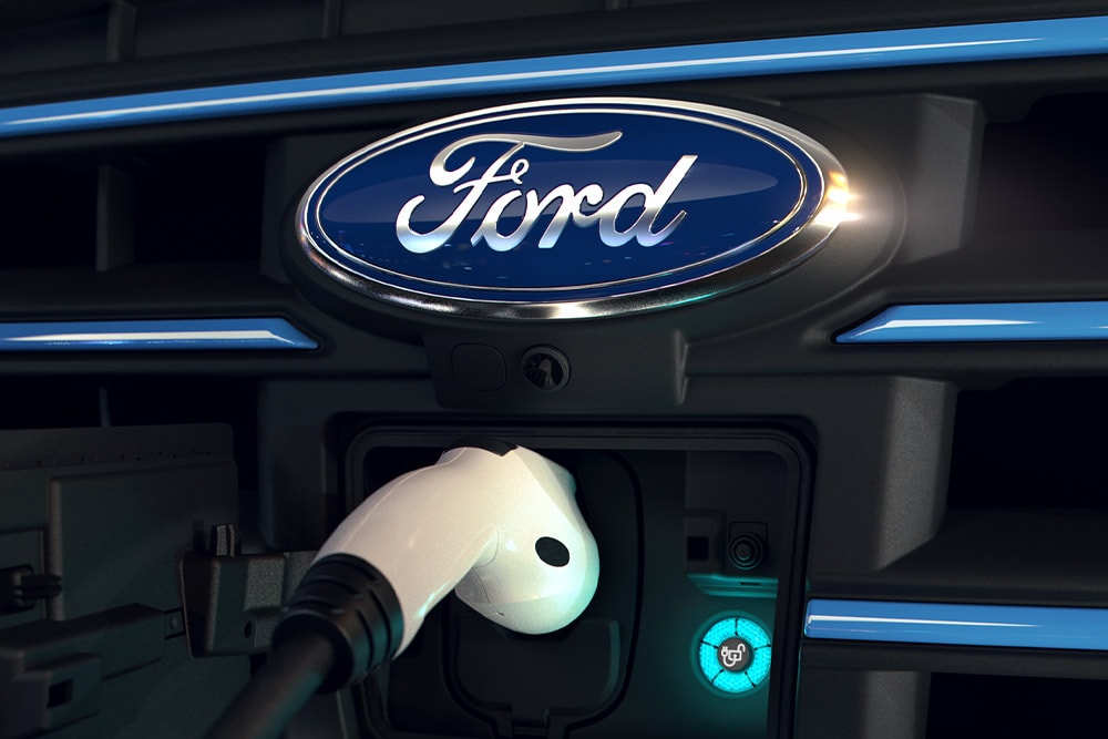 Primo piano di un cavo di ricarica bianco collegato alla porta di ricarica anteriore di un veicolo elettrico Ford.