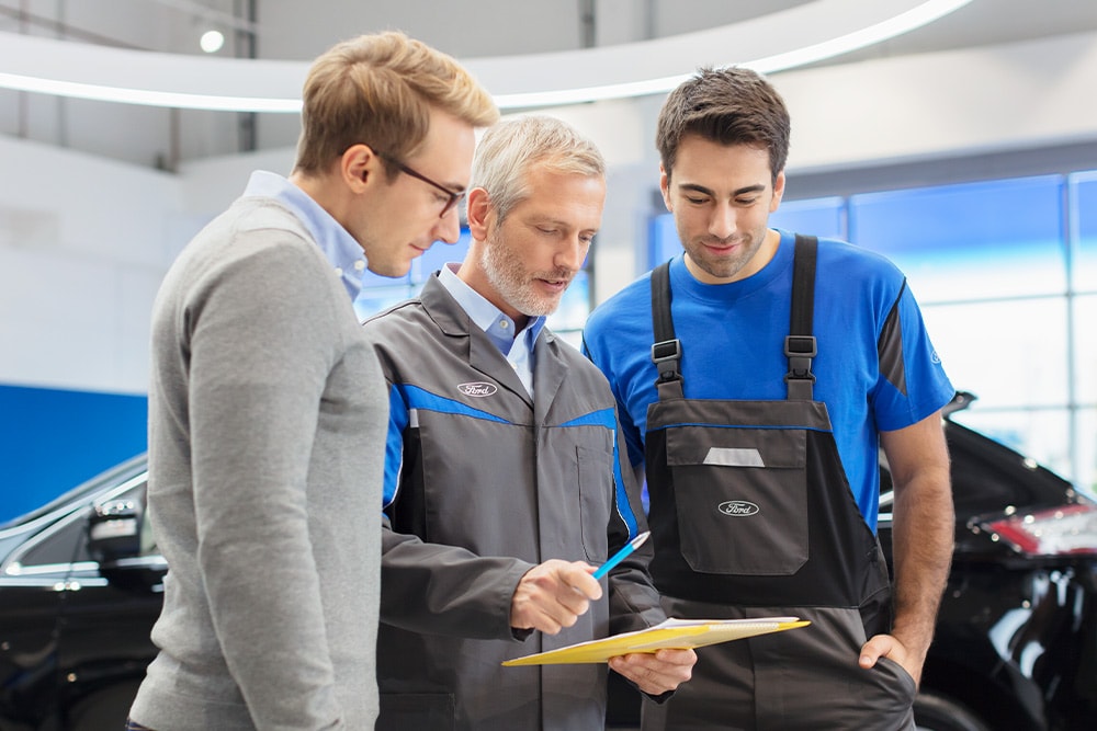 Tre esperti discutono le opzioni di veicoli pronti all'uso presso un Ford Transit Centre.