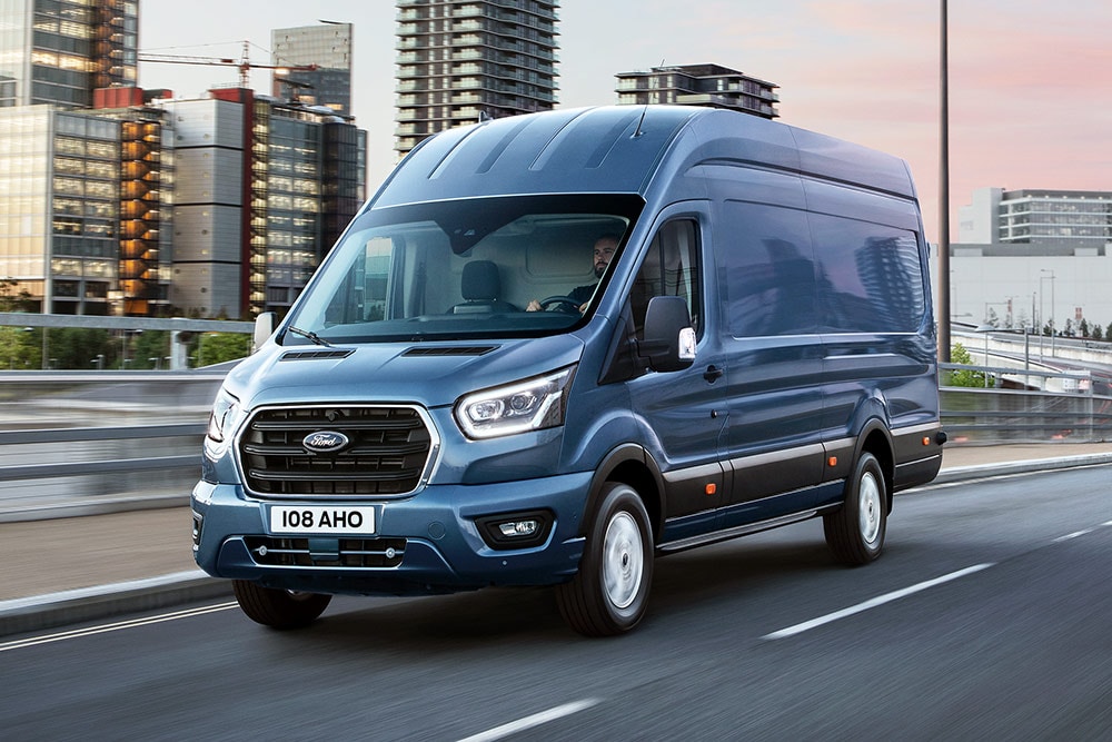 Un Ford Transit color argento che attraversa un paesaggio urbano.