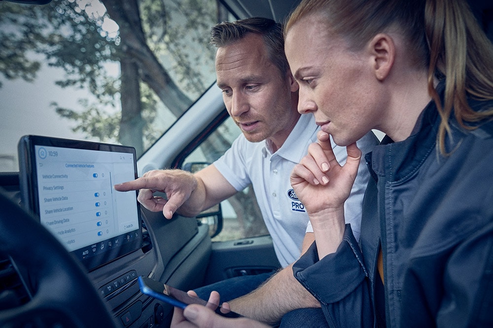 Diversi veicoli elettrici della flotta Ford parcheggiati di fronte a un magazzino.