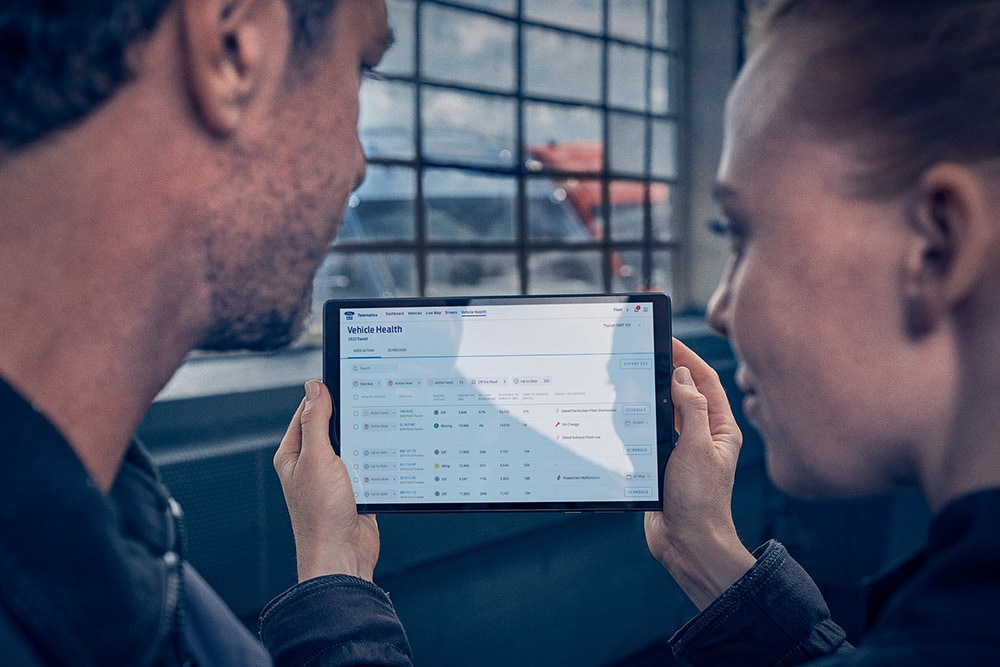Gestori di flotte che esaminano la telematica dei veicoli su un tablet.