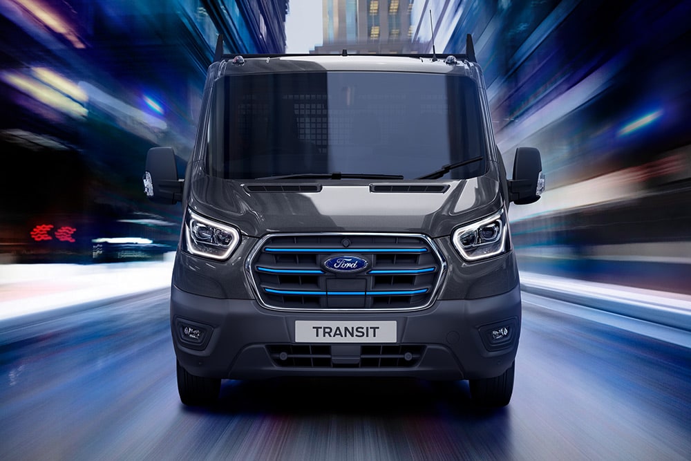 Ford Pro Transit color argento parcheggiato in un cantiere, con operai edili sullo sfondo.