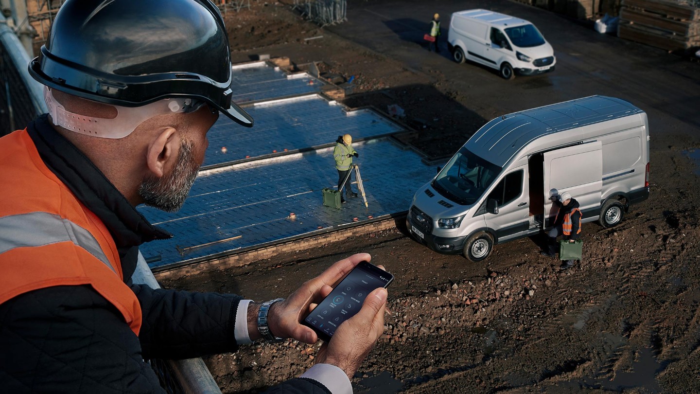 Person in high viz jacket looking down on building site with Ford Van