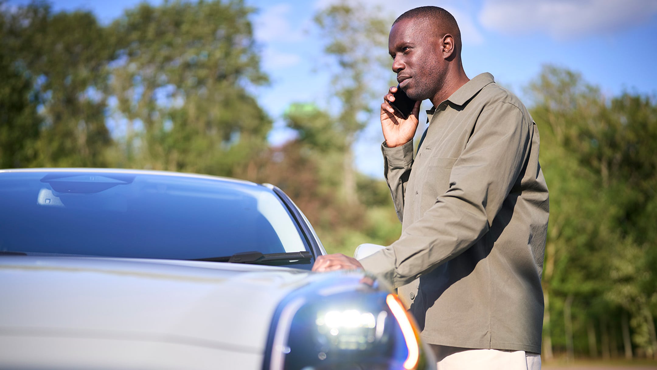 A person places a red warning triangle by a car that has broken down at the side of a road.