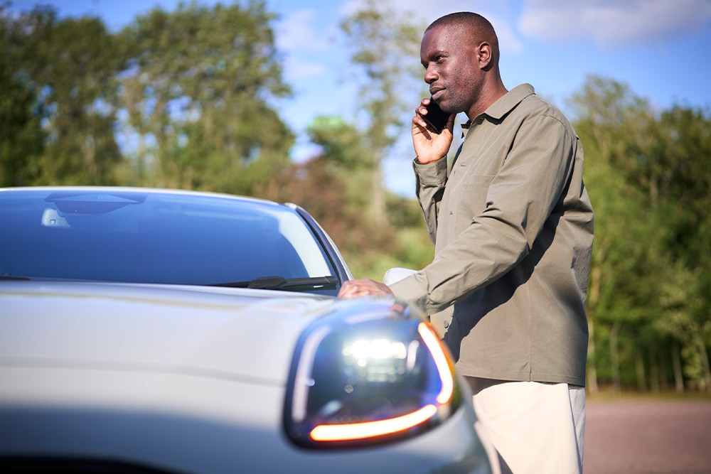 Man standing next to car on the road side
