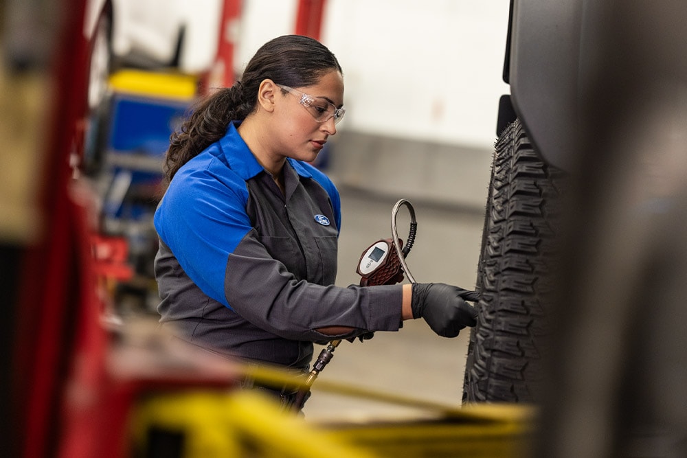 Tecnico addetto alla manutenzione Ford che serra i bulloni delle ruote